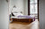 full size Bett 2.0, an eco-friendly bed frame by RIAB USA, on parquet floor with purple comforter and modern silver lamp